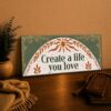 Create a life you love, close-up lettering on sage green boho canvas